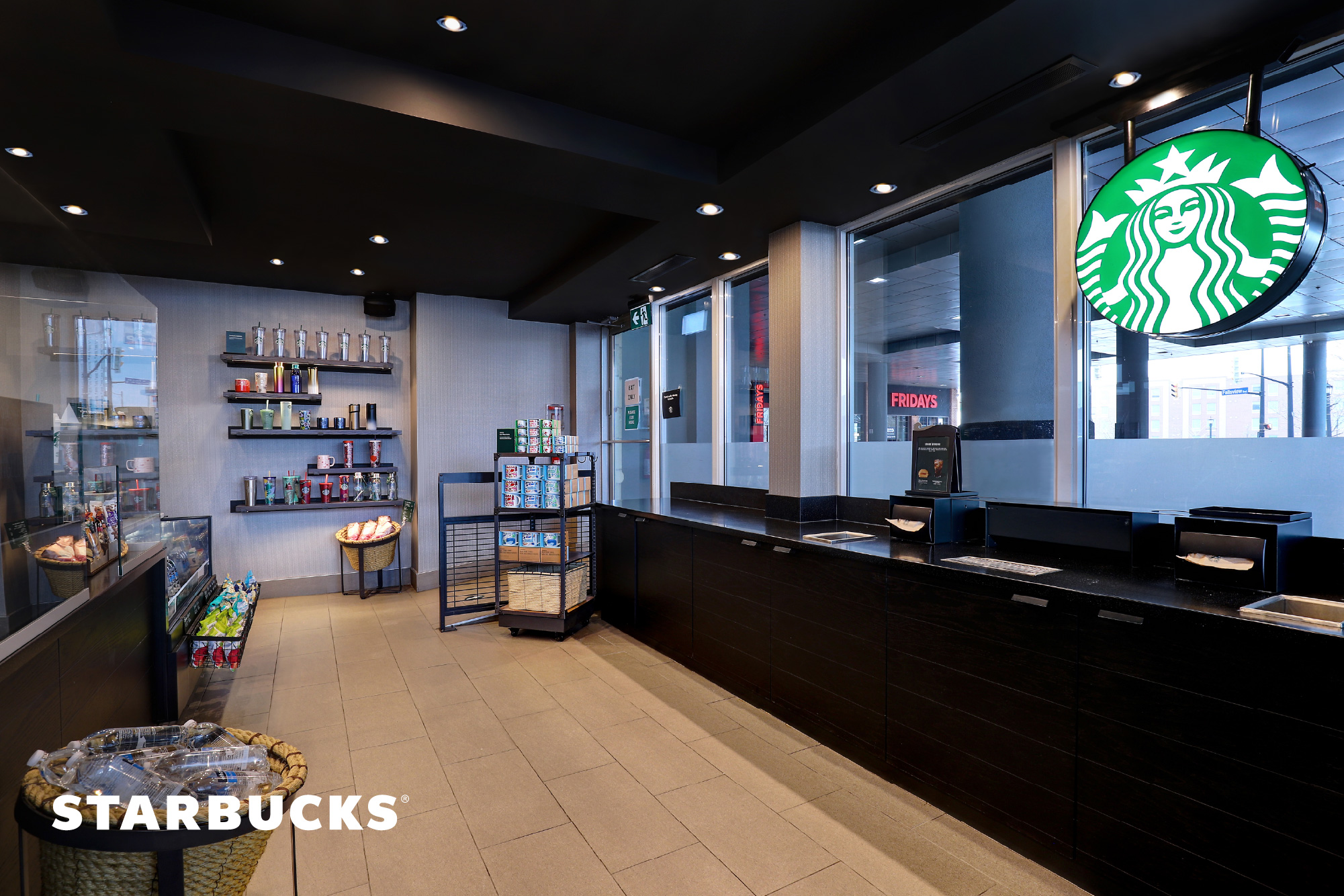 Starbucks interior with a clean, minimalist space with dark wood accents, a streamlined counter and merchandise for purchase.